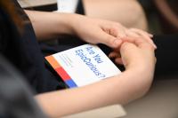 A close-up of a woman's hands around a large card containing the sentence "Are you epic curious?" is shown.